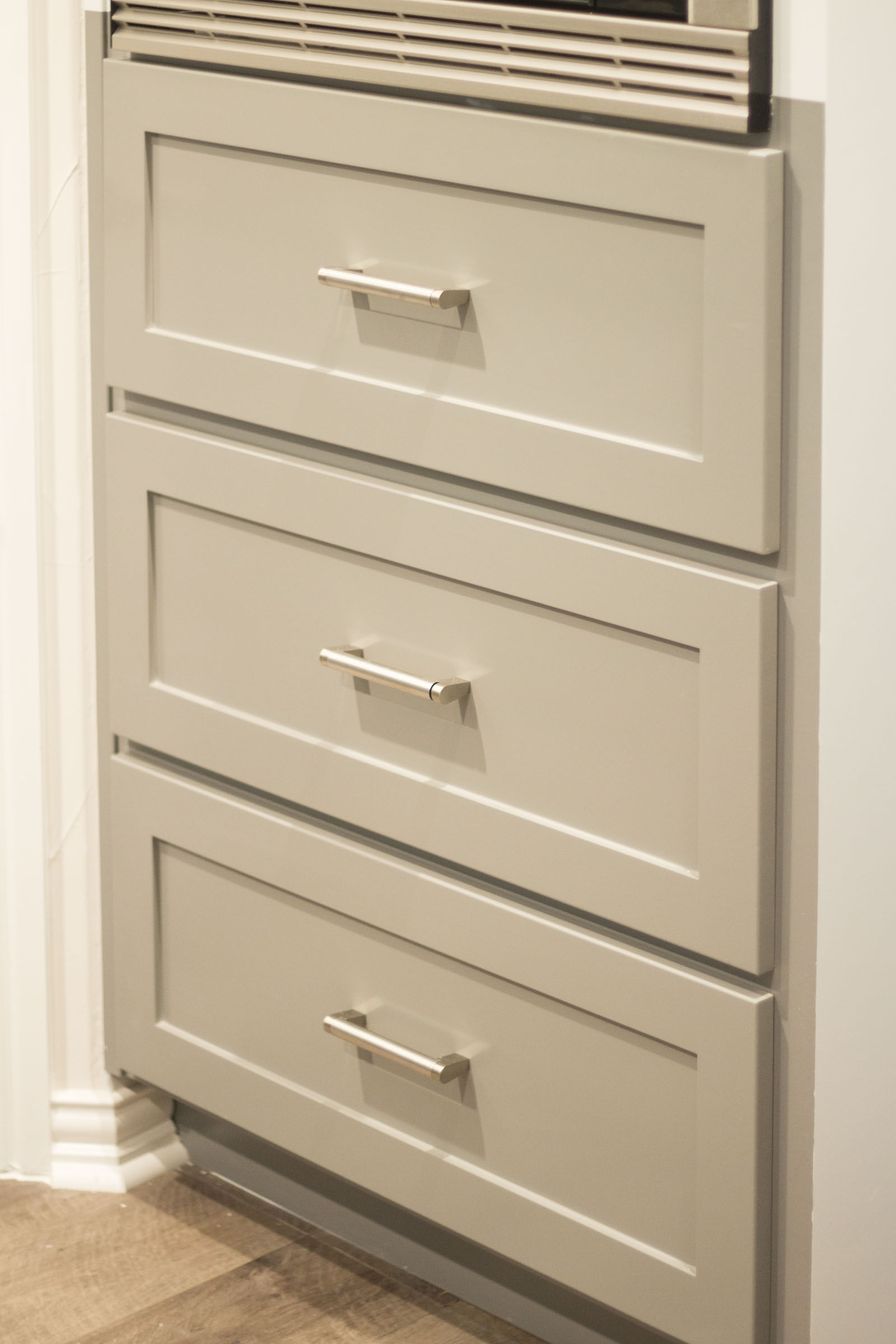 Close up photo of grey shaker style cabinet drawers and matte silver pulls