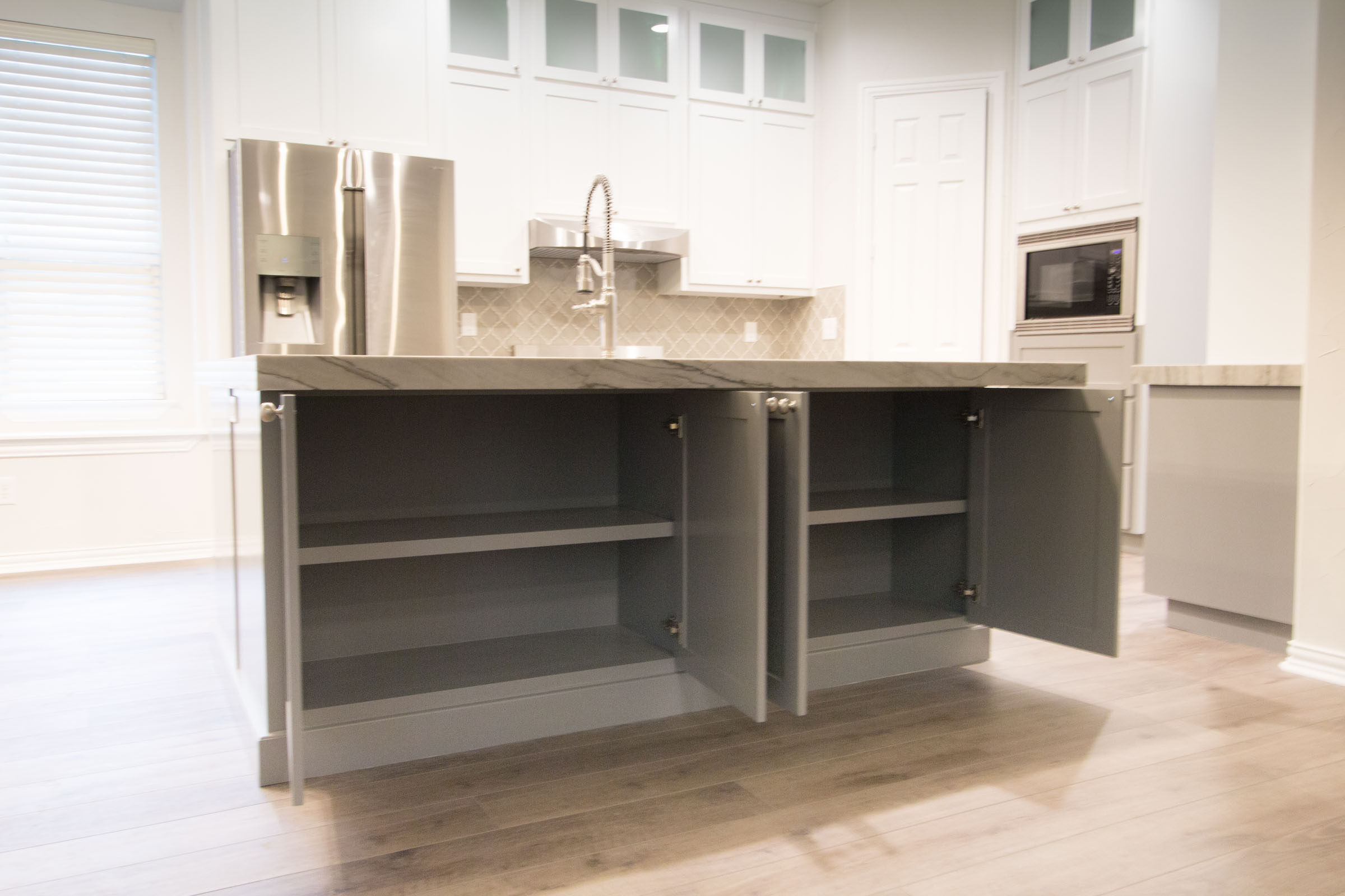 Contemporary kitchen remodel, showcasing under island storage space, open cabinet doors, bar island with sink