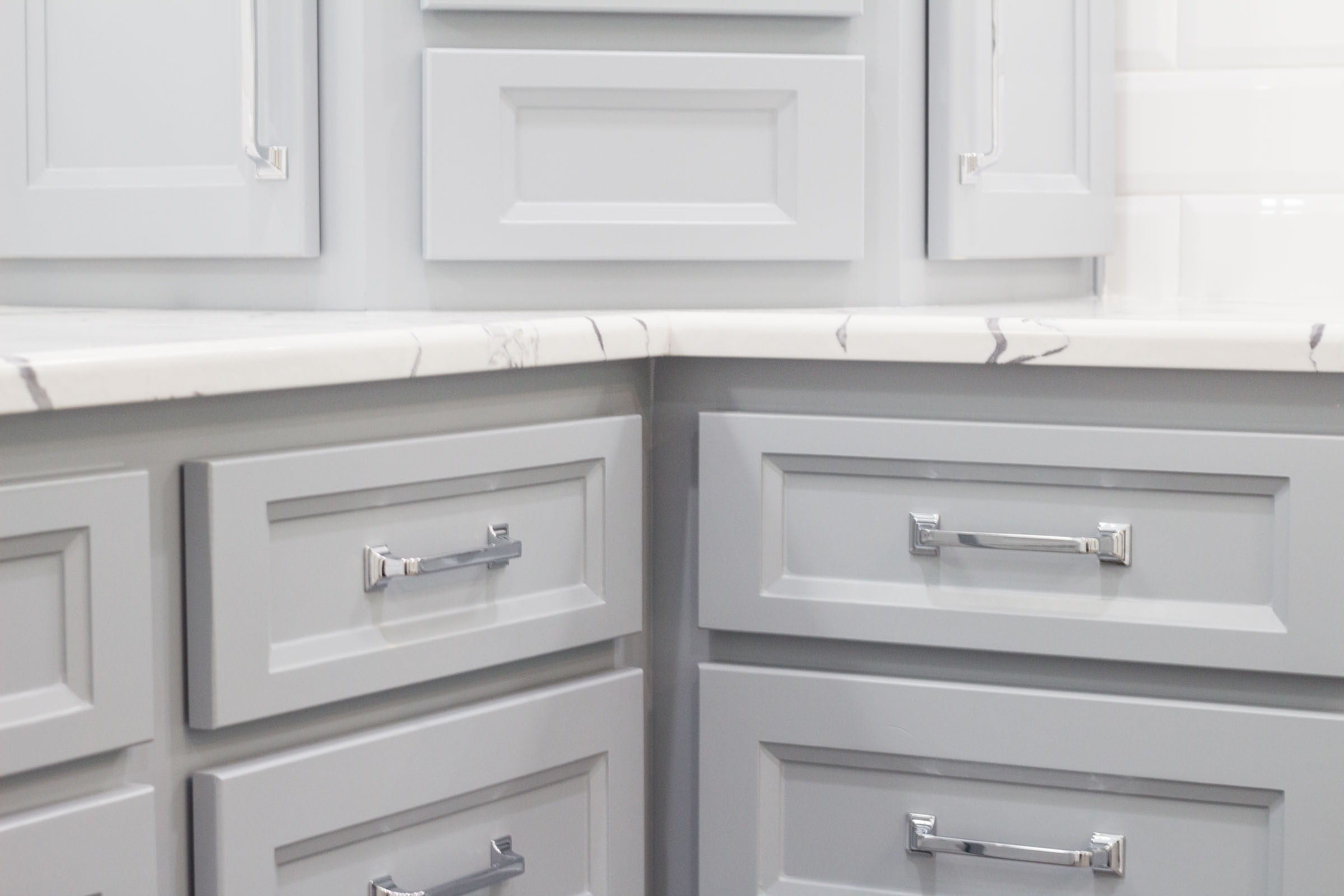 Close up of contemporary bathroom cabinets, shaker style, chrome drawer hardware, white and grey mixed granite
