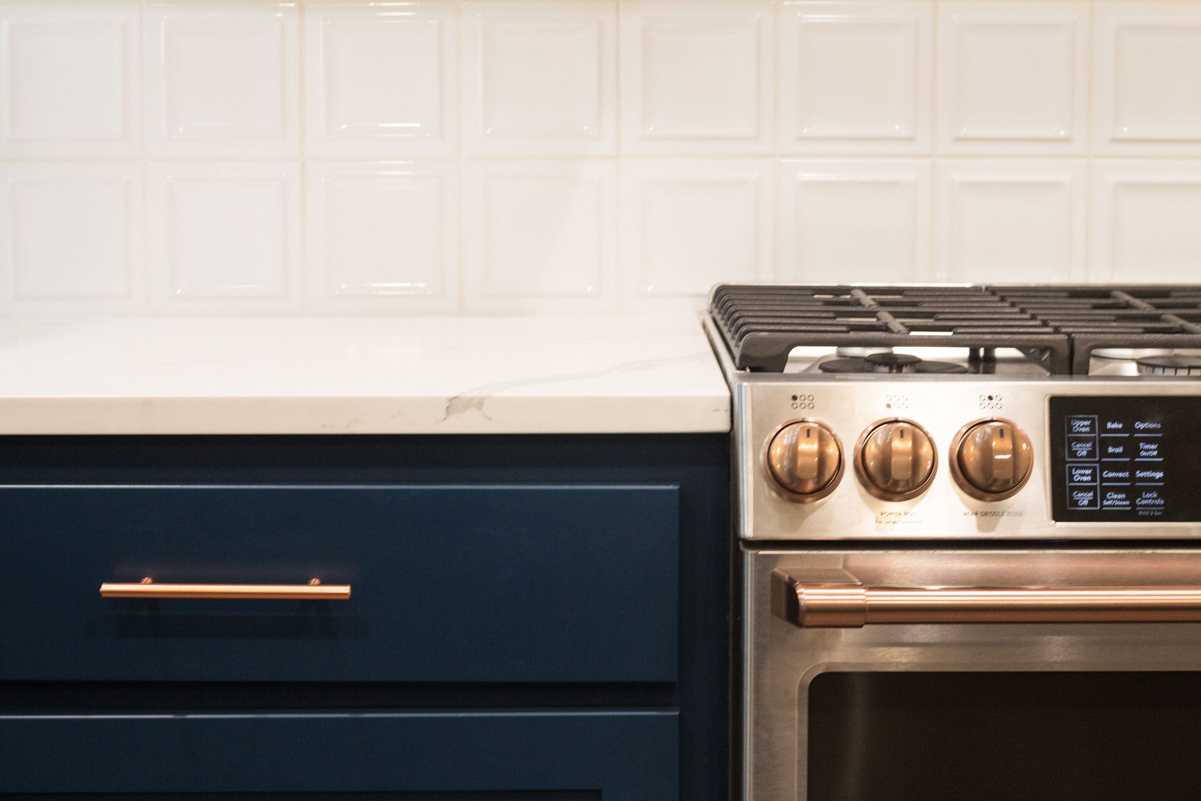Navy drawers, stainless steel gas range, copper accents, kitchen remodel