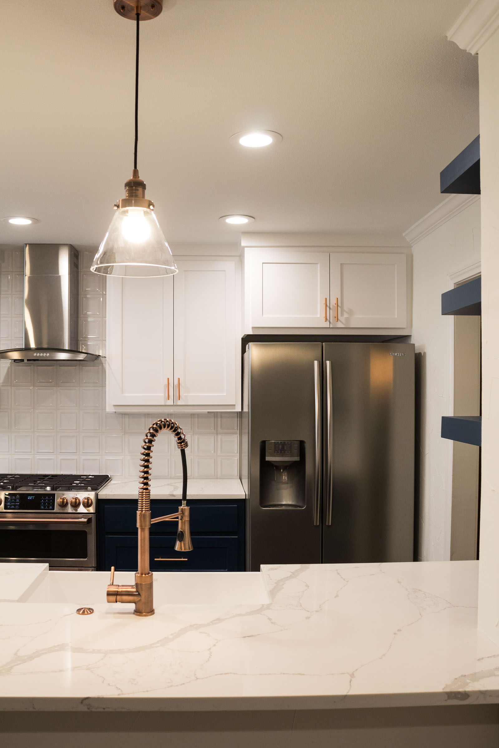 Kitchen remodel with white counters, navy cabinets, and copper hardware