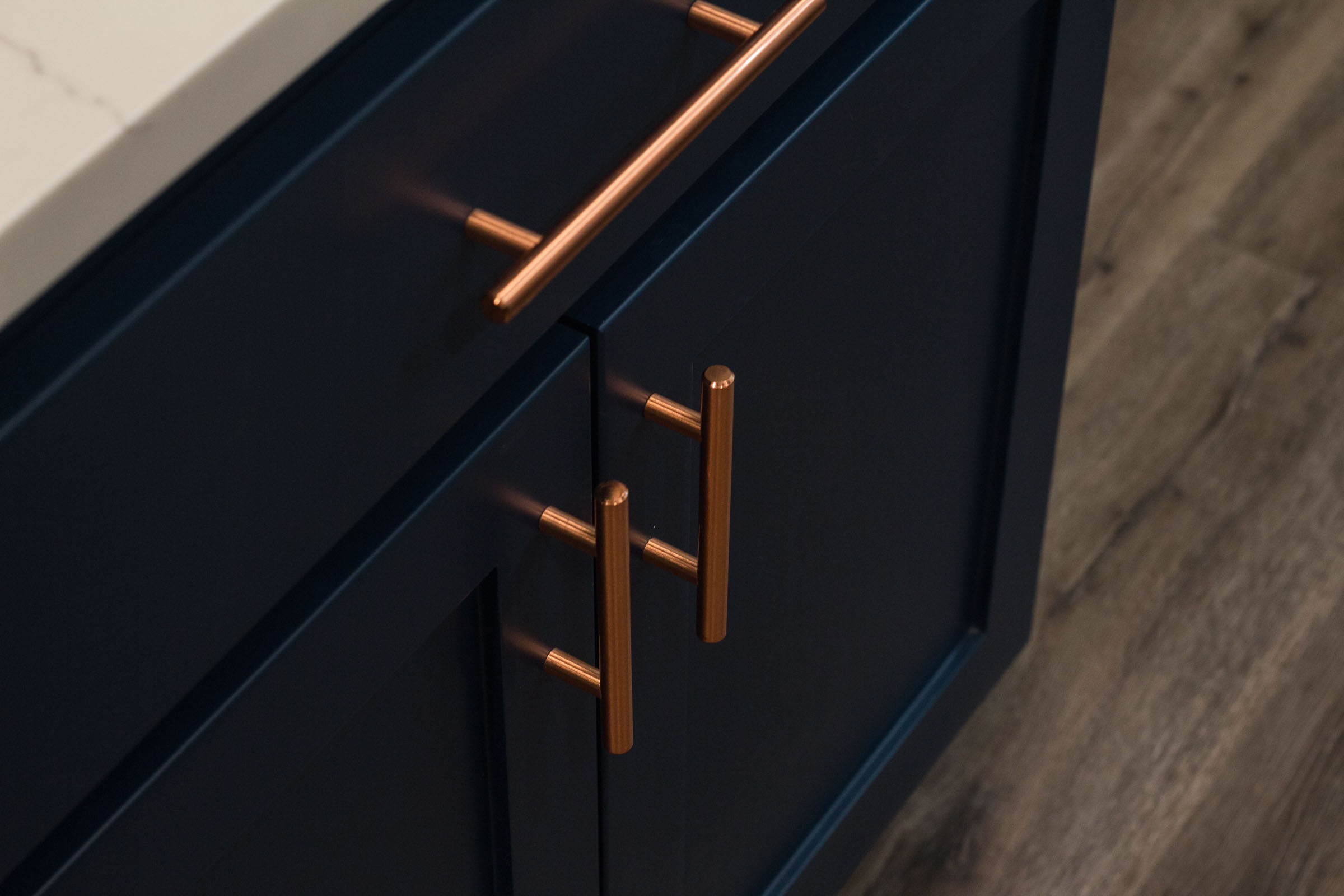 Close up of navy lower cabinets and copper drawer pulls