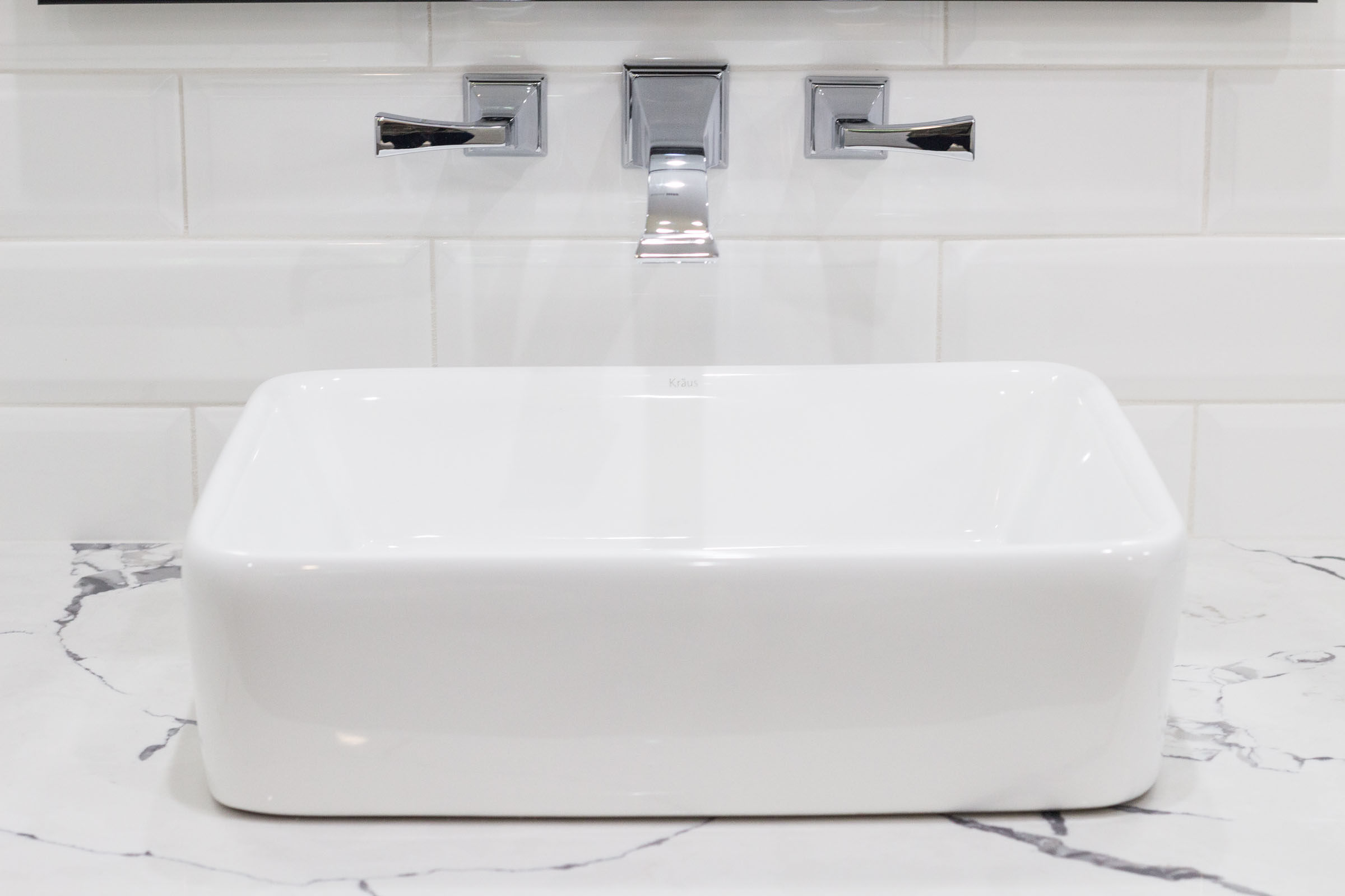 Countertop pedestal bathroom sink with white and grey granite, chrome sink faucet, and white subway tile backsplash