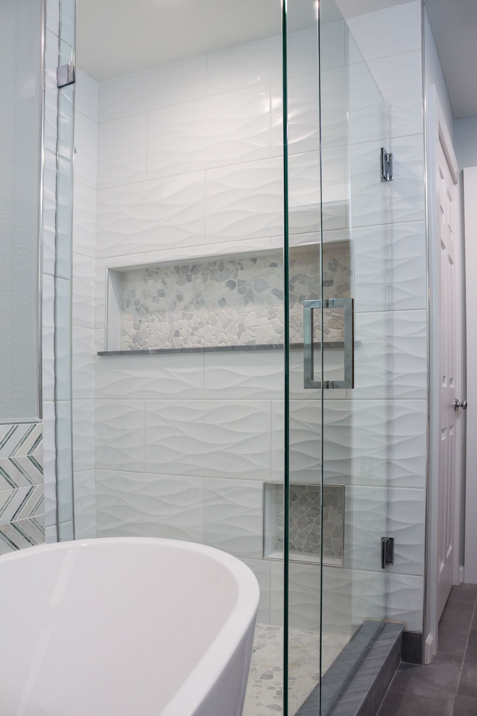 Bathroom remodel with walk in shower, glass doors, pedestal bathtub, and dark grey flooring