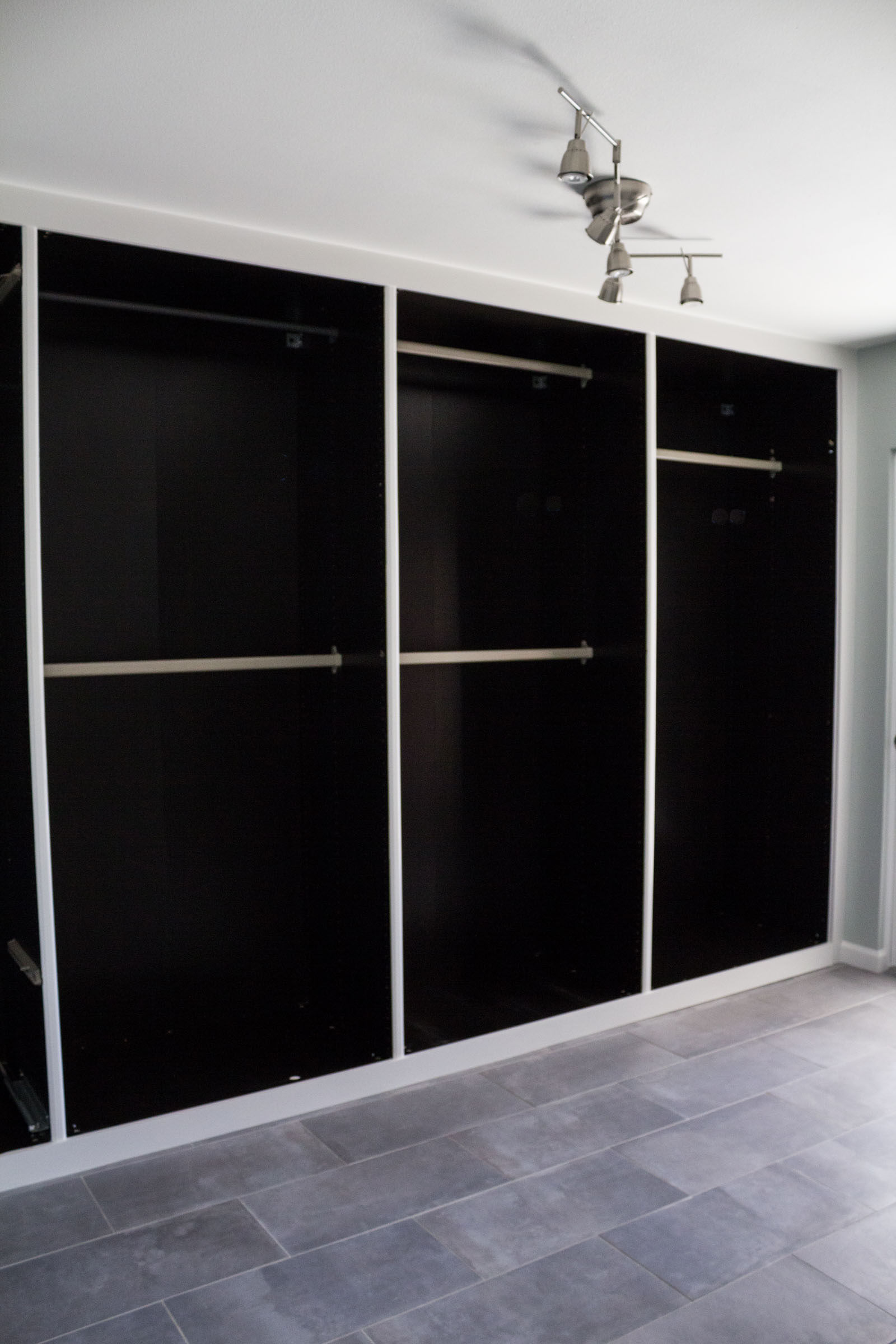 Doorless black bedroom closet built ins with clothing rods